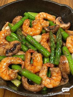 shrimp and asparagus stir fry in a skillet on a wooden table top