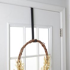 a wreath is hanging on the front door window sill with wheat stalks in it