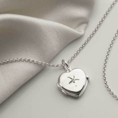 "Our beautiful Sterling Silver diamond Kissed Locket has a wonderfully classic design making it a timeless piece which will be loved and treasured for years to come. The front of the locket is embellished with a single round cut diamond and the back has a luxurious plain polished surface, perfect for engraving a message on. In addition, this locket is designed to hold two photos. This locket comes complete with a sterling silver belcher chain available in five different lengths. So why not make this a truly personal gift by having your own special message engraved, by us, on this eye catching locket. To order this locket simply select the chain length and the font you would like us to use from the drop down menu, you can select \"no engraving\" if you would like us to leave it blank. Then Timeless Silver Heart Pendant Jewelry, Timeless Silver Locket Jewelry, Classic White Gold Locket Necklaces, Classic White Gold Locket Necklace, Elegant Round Pendant Locket Necklace For Anniversary, Timeless Silver Heart Pendant Necklace, Elegant Round Sterling Silver Locket Necklace, Timeless Silver Jewelry For Valentine's Day, Timeless Pendant Locket Necklace For Anniversary