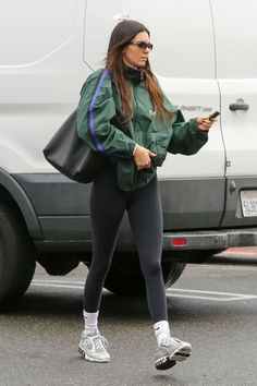 a woman is walking down the street while looking at her cell phone and wearing leggings