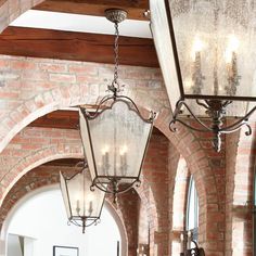 a chandelier hanging from the ceiling in a room with brick walls and arched doorways