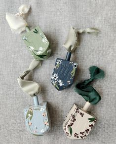 four small vases with flowers and ribbons tied around them on a gray cloth surface