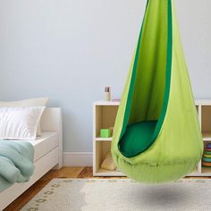 a green hanging chair in a child's bedroom next to a book shelf and bed