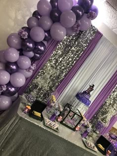 purple and silver balloons are hanging from the ceiling in front of a table with desserts