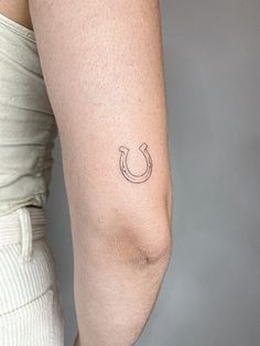 a woman's arm with a horseshoe tattoo on the left side of her arm