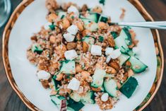 a white plate topped with cucumber, chickpeas and feta cheese