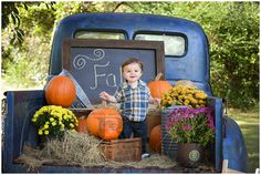 a little boy sitting in the back of a truck with pumpkins