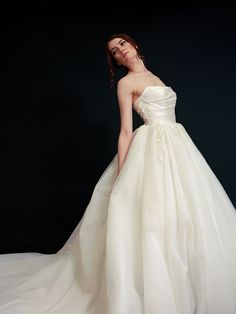 a woman in a white wedding dress posing for the camera with her hands on her hips