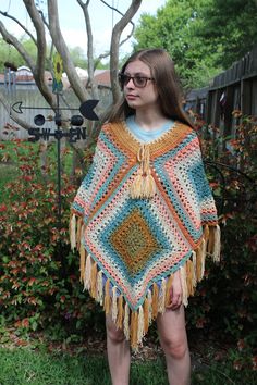 This crochet poncho is a perfect summertime boho beach cover-up. It's hand-crocheted with a soft blue, peach, and tan acrylic yarn. It has a drawstring so it fits most adults, a partially netted pattern for good airflow, and a decorative fringe. The poncho measures about 30 inches around the collar (uncinched), and 25 inches down the middle.  The model is 5'3" and 100 lbs. Care Instructions: machine wash warm and dry, or dry flat. Pattern by wilmade Sheepberry's Sustainability Practices -Used or discounted yarn (when possible) -Making use of all fiber scraps -Recycled and reused packaging Beige One Size Poncho For The Beach, Bohemian Poncho In Yarn One Size, Bohemian Style Yarn Poncho One Size, Hippie Multicolor Poncho For Beach, Bohemian One Size Yarn Poncho, Handmade One Size Poncho For Beach, Handmade Poncho For Summer Beach, Blue Bohemian Poncho For Spring, Handmade Poncho For Beach In Summer