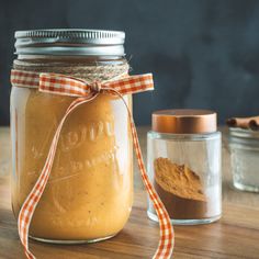 a jar filled with peanut butter sitting on top of a wooden table next to two jars