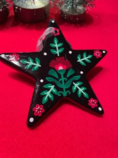 a black star ornament decorated with flowers and leaves on a red tablecloth