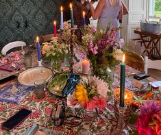 a woman standing in front of a table filled with flowers and candles