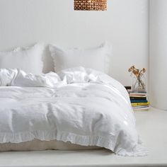 a bed with white sheets and pillows in a room