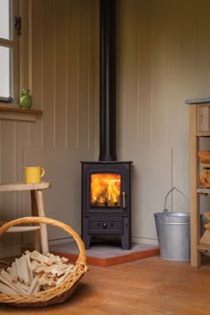 a wood burning stove sitting inside of a living room next to a basket filled with logs