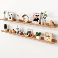 two wooden shelves with pictures and plants on them