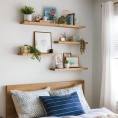 a bed room with a neatly made bed and shelves on the wall above it's headboard