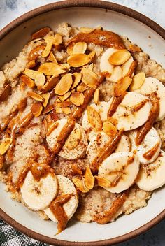 a bowl filled with oatmeal topped with bananas and sliced almonds on top