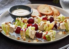 an appetizer plate with grapes, apples, and bread on it is ready to be eaten