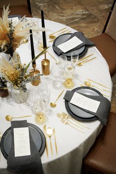 the table is set with black and gold place settings