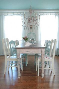 a dining room table with four chairs and a chandelier hanging from the ceiling