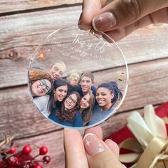 a person holding up a glass ornament with photos on it