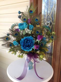 a vase filled with blue flowers and peacock feathers