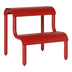 a red plastic bench sitting on top of a white floor next to a wooden table