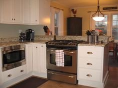 a kitchen with white cabinets and stainless steel stove top oven in the center of the room