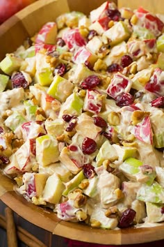 a salad with apples, cranberries and walnuts in a wooden bowl on a table