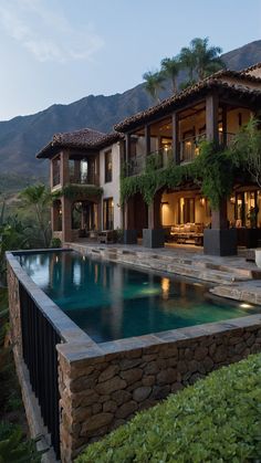 a large house with a pool in front of it and mountains in the back ground