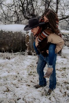 a man carrying a woman on his back in the snow