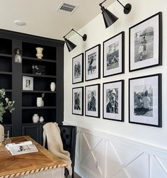 black and white photographs hang on the wall above a desk