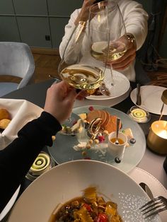 two people toasting wine glasses over a meal