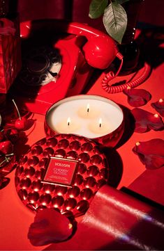 a red table topped with two candles next to an apple and other items on top of it