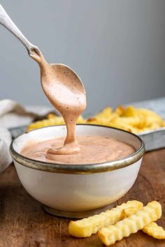 a spoon full of peanut butter dip in a bowl with crackers on the side