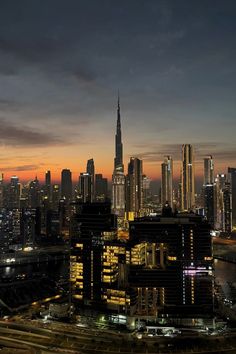 the city skyline is lit up at night, with skyscrapers in the foreground