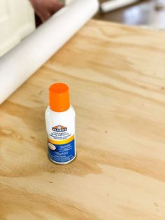 an orange and white bottle sitting on top of a wooden table