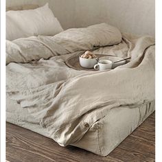 an unmade bed with two coffee cups on it