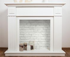 a white fireplace mantel with candles and decorations on the mantle, in front of a brick wall