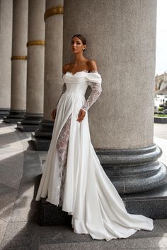 a woman in a white wedding dress standing next to columns with her hands on her hips