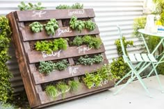 a wooden pallet filled with lots of green plants next to a white chair and table