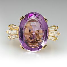 This exquisite ring is centered with one (1) oval mixed cut natural amethyst set into a four-prong setting. The shoulders of the ring are each accented with three (3), channel set, tapered baguette cut diamonds. The ring measures 15.9mm at the top, rises 9.4mm above the finger, tapering to 3.2mm wide and 1.3mm thick at the base of the shank. This ring is currently a size 6.25. Luxury Oval Amethyst Ring With Center Stone, Formal Lavender Amethyst Ring With Oval Shape, Luxury Purple Oval Gemstones, Formal Lavender Oval Amethyst Ring, Oval Amethyst Ring With Gemstone Accents For Formal Occasions, Exquisite Oval Amethyst Ring For Formal Occasions, Purple Baguette Cut Rings For Formal Occasions, Elegant Oval Purple Rings, Art Deco Oval Purple Amethyst Ring