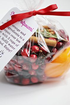 a bag filled with lots of fruit sitting on top of a white table next to a red ribbon