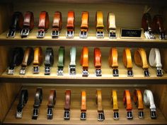 many different colored belts are on display in a store window with wooden shelves and wood flooring