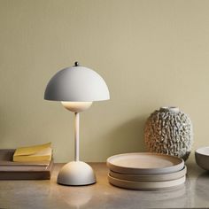 a table topped with plates and a white lamp next to a bowl on top of a counter