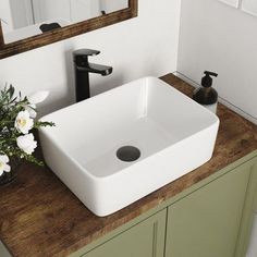 a white square sink sitting on top of a wooden counter next to a bathroom mirror