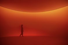 a person standing in the middle of a room with red light coming from behind them