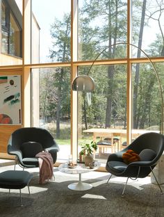 a living room filled with furniture next to large glass windows covered in wood paneling