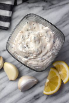 an image of a lemon and garlic dip in a glass container on a marble table