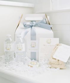 a white gift box with blue ribbon and some items on it sitting on a table